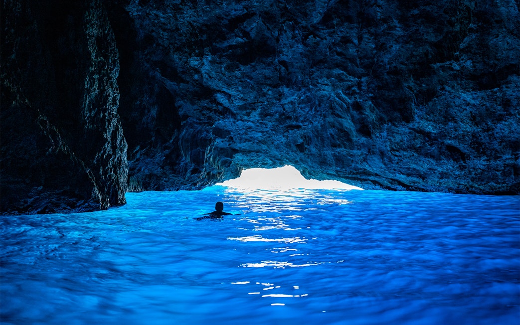 Swimmer entering Blue Cave on Dubrovnik boat tour.