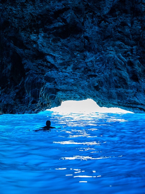 Swimmer entering Blue Cave on Dubrovnik boat tour.