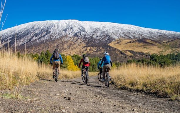 Cyclists on a trail with Mount Etna in the background, Sicily.