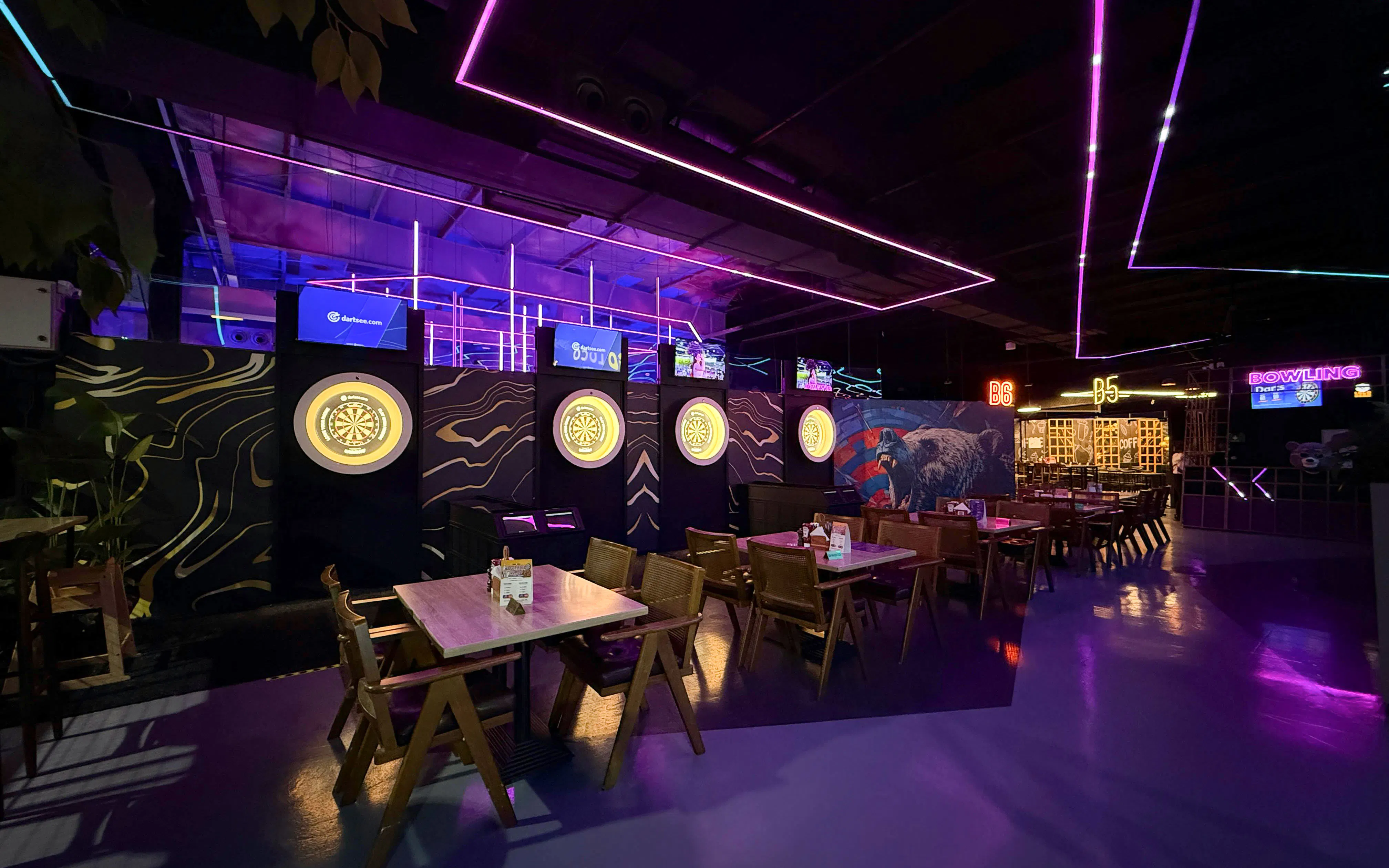 Dartboards and dining tables in neon-lit area at Loco Bear, Dubai.