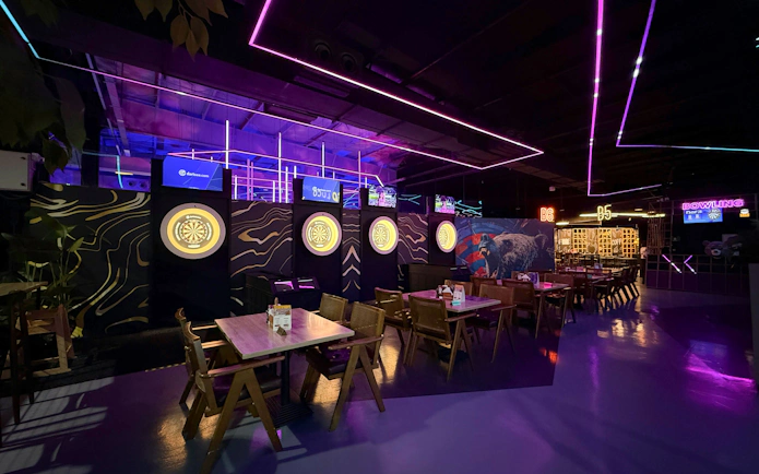 Dartboards and dining tables in neon-lit area at Loco Bear, Dubai.