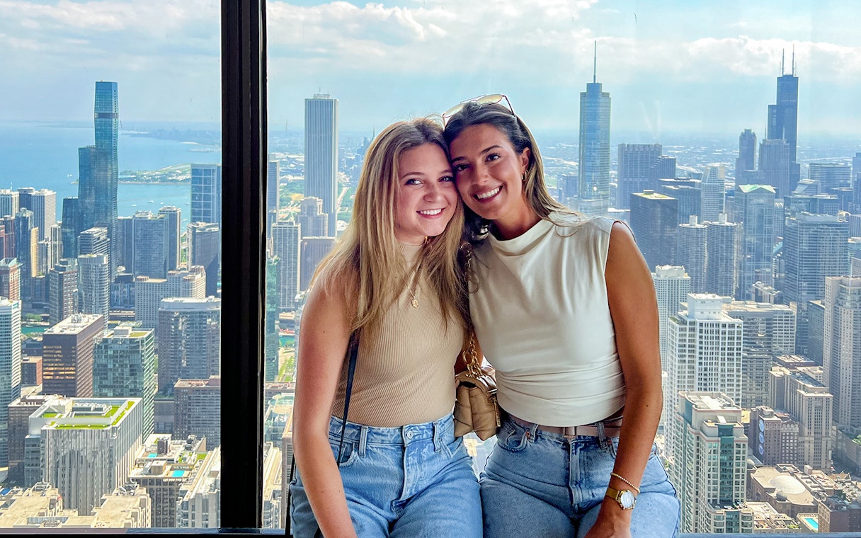 Two people enjoying a view of the Chicago skyline from a high-rise, part of the Sip & View tour.