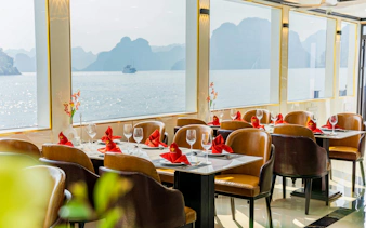 Dining area on Ha Long Bay luxury cruise with sea view through large windows.