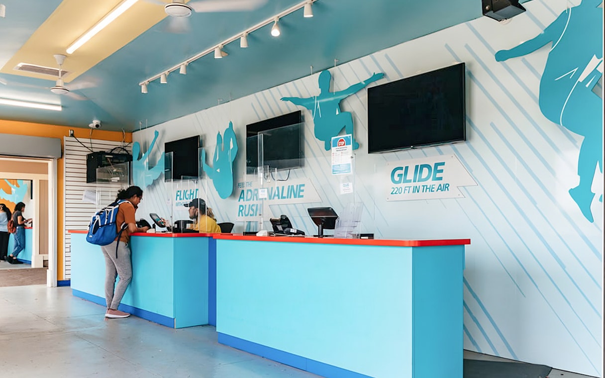 Zipline To The Falls ticket counter with customer and staff interaction.