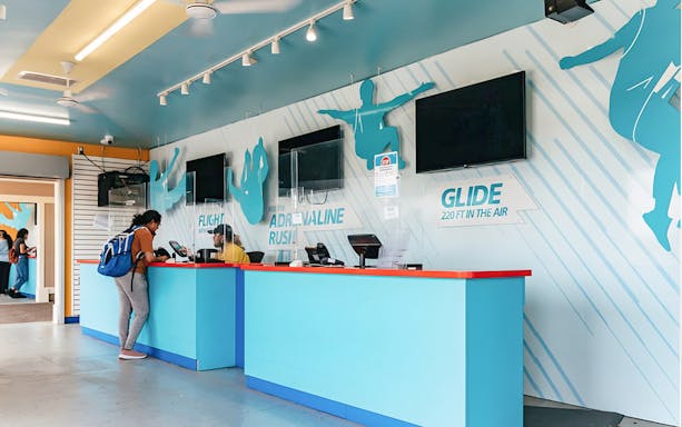 Zipline To The Falls ticket counter with customer and staff interaction.