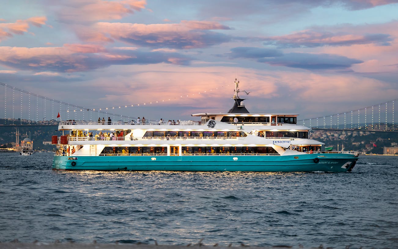 Bosphorus Dinner Cruise ship sailing at sunset with Istanbul skyline in the background.
