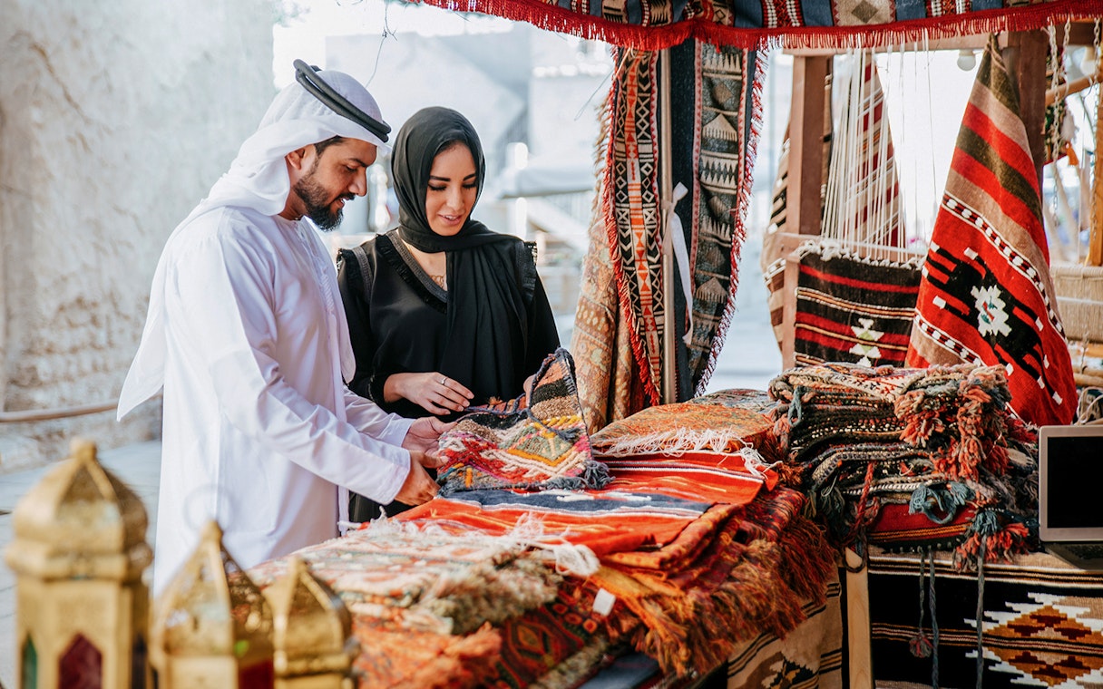 Couple browsing traditional rugs at Heritage Village market, Dubai.