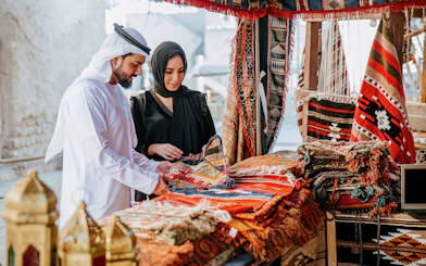 Couple browsing traditional rugs at Heritage Village market, Dubai.