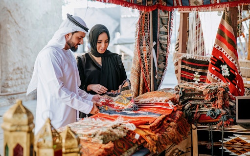 Couple browsing traditional rugs at Heritage Village market, Dubai.
