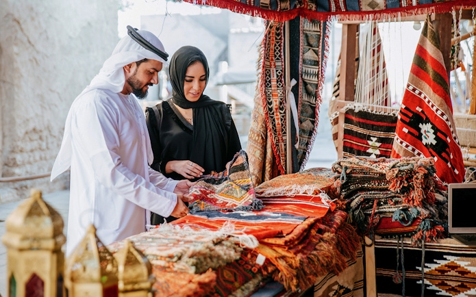 Couple browsing traditional rugs at Heritage Village market, Dubai.