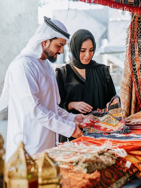 Couple browsing traditional rugs at Heritage Village market, Dubai.