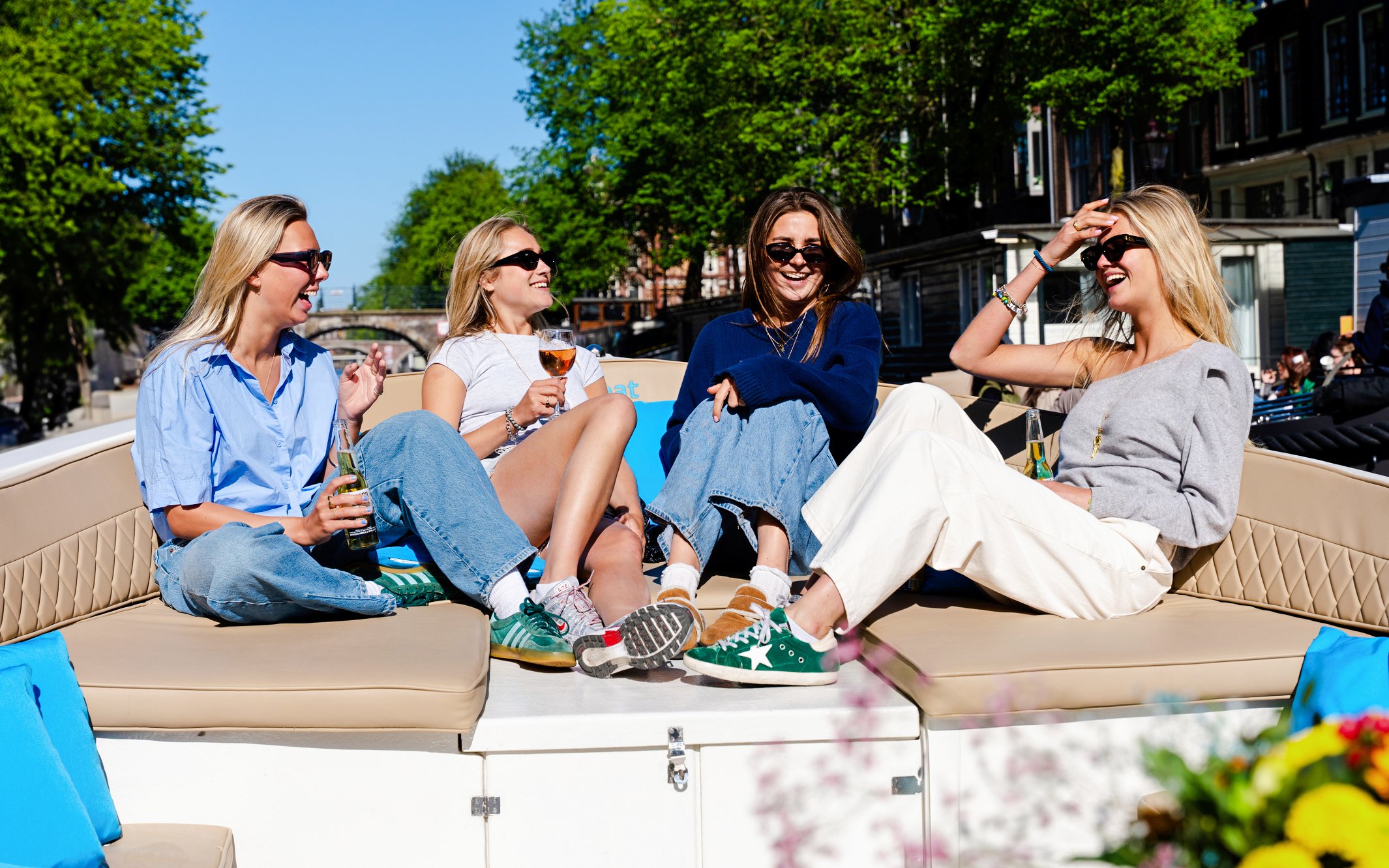 Friends enjoying drinks on an open boat canal cruise in Amsterdam.