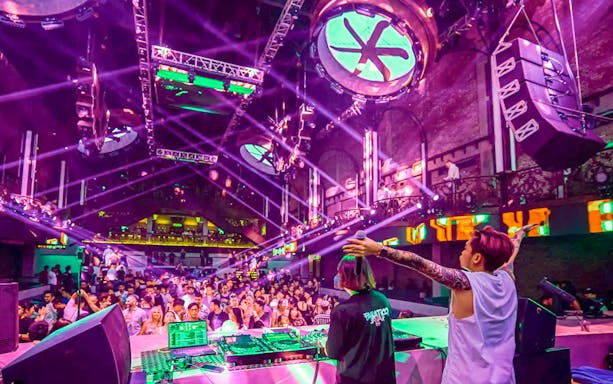 Attendees enjoying live music at CKay Event, Atlas Beach Club, Bali with vibrant lights.