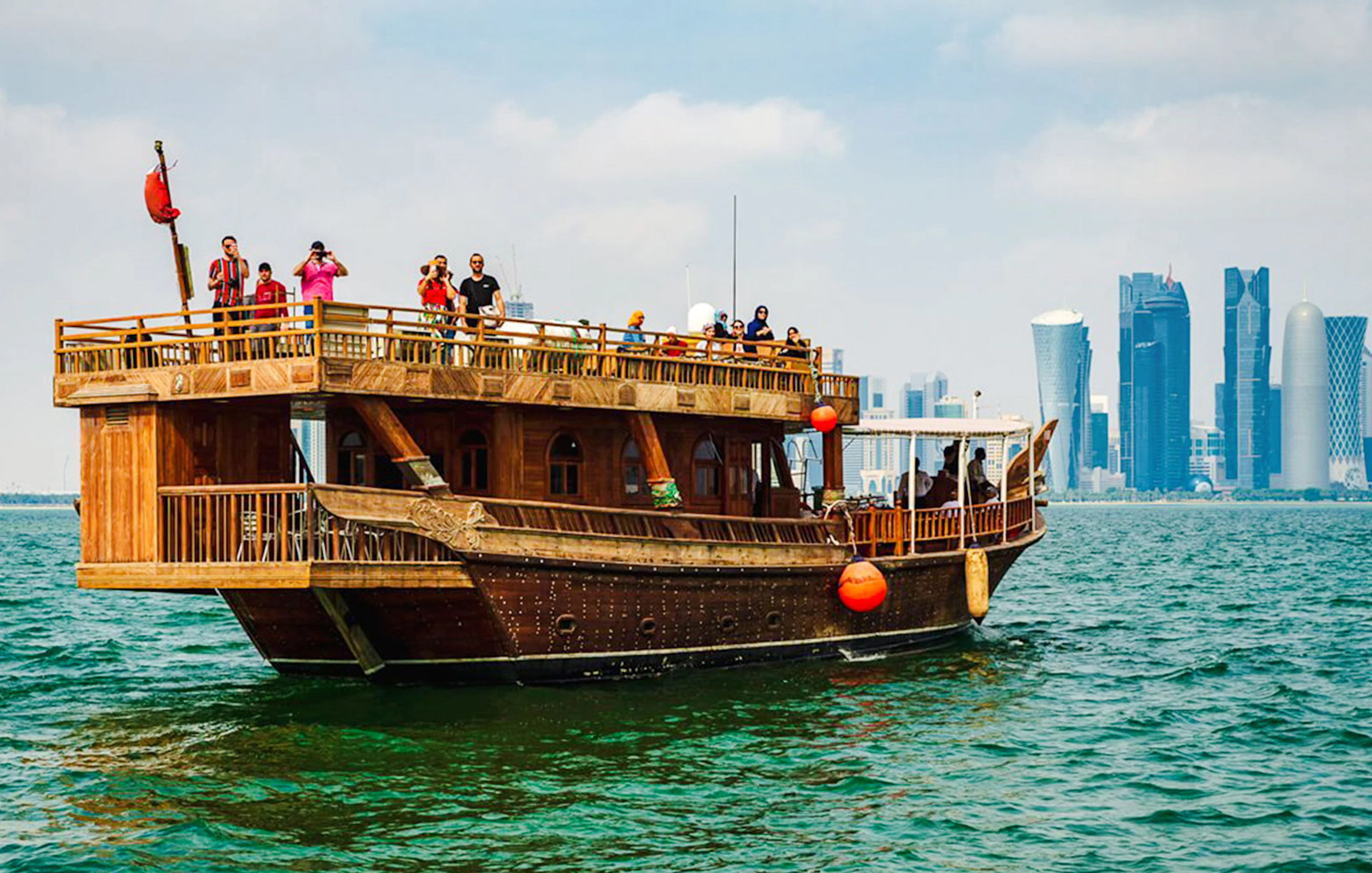 Dhow boat sailing with Doha city skyline in the background.