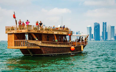 Dhow boat sailing with Doha city skyline in the background.