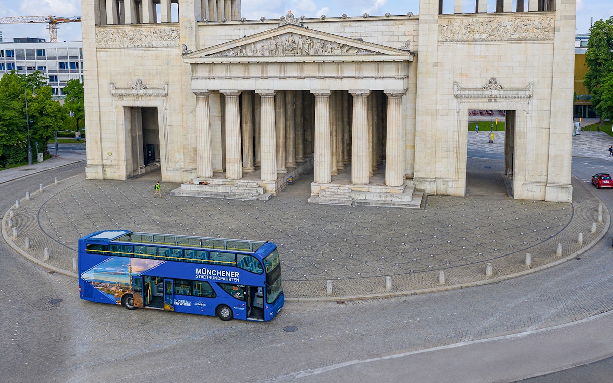 Open-top tour bus in front of Munich's Propylaea on a Hop-On/Hop-Off Express Tour.