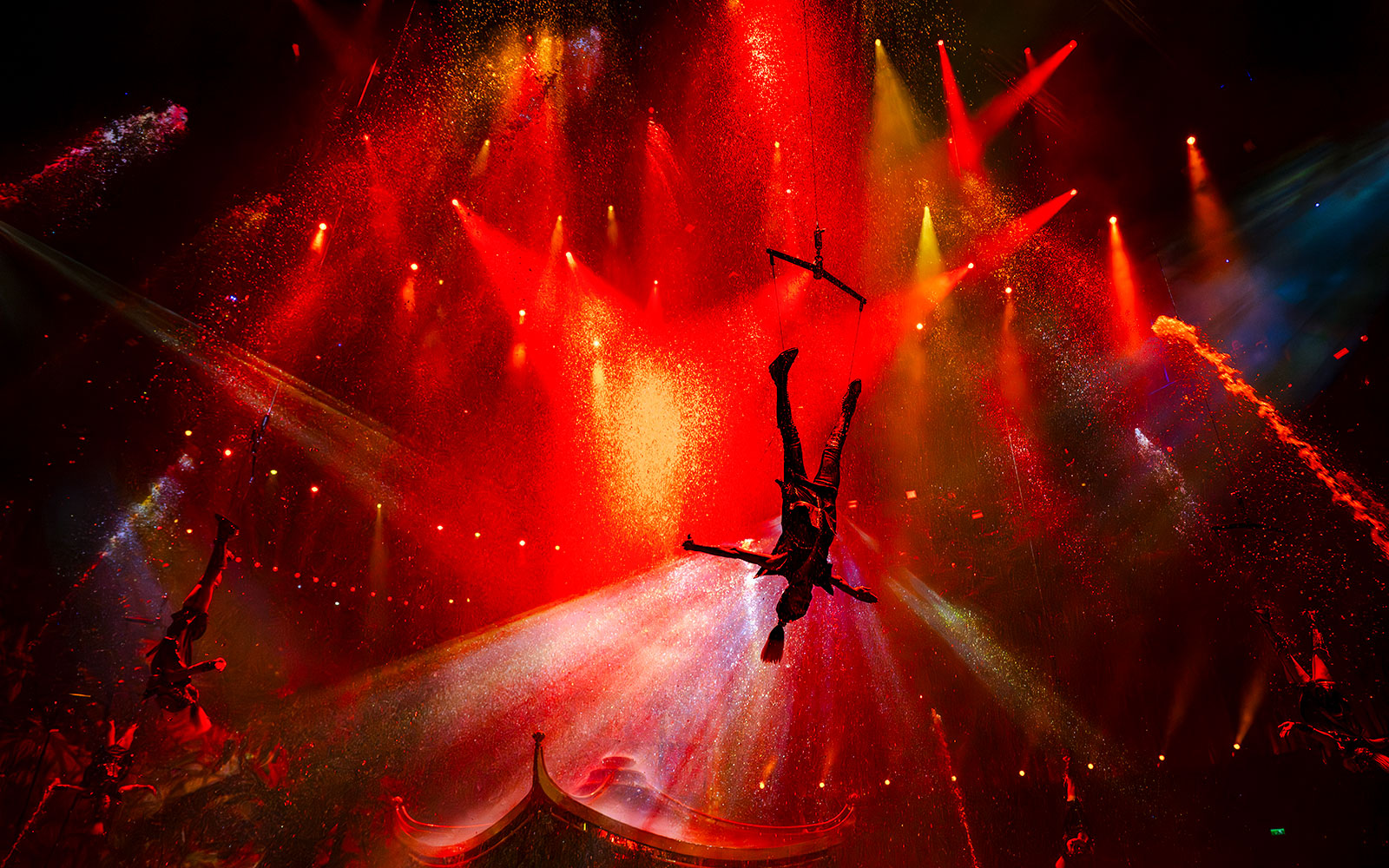 Acrobat performing mid-air during House of Dancing Water show with vibrant red lighting.