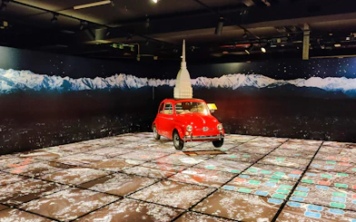 Red car display at National Automobile Museum, Turin, Italy with mountain backdrop.