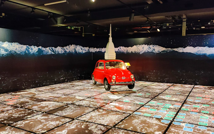Red car display at National Automobile Museum, Turin, Italy with mountain backdrop.