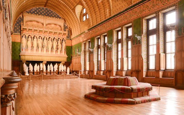 Interior of the Castle of Pierrefonds with statues and ornate wooden details.