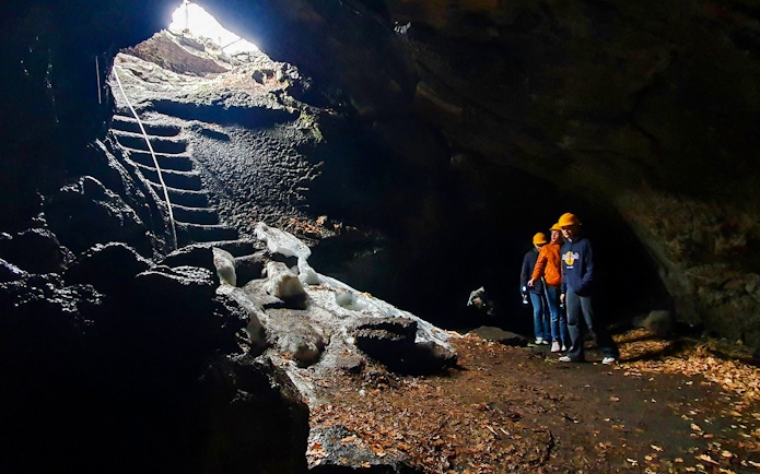Visitors exploring a cave on Mount Etna with helmets and flashlights.