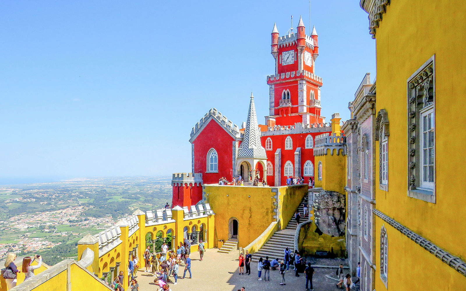 Pena Palace in Sintra with tourists exploring the colorful architecture.