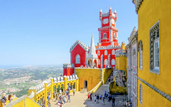 Pena Palace in Sintra with tourists exploring the colorful architecture.