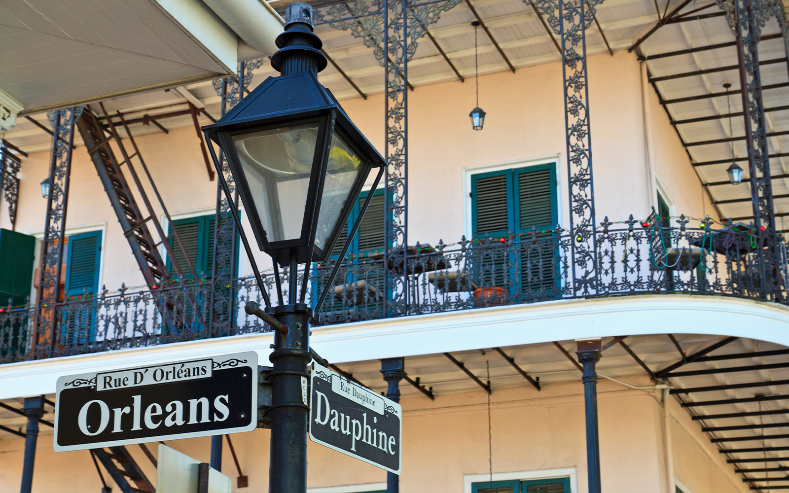 Orleans and Dauphine street signs with Gardette-LePrete House balcony in New Orleans.
