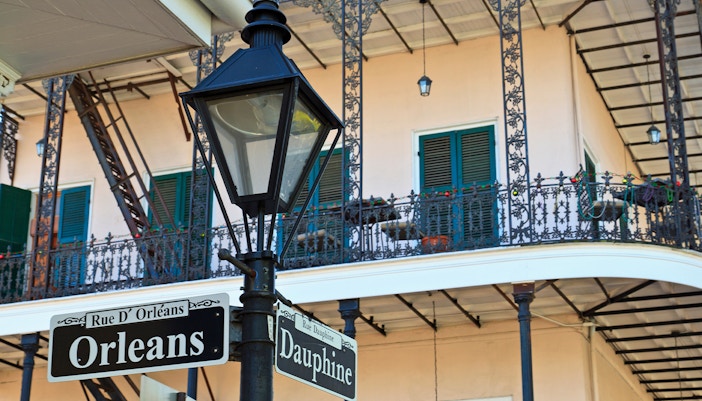 Orleans and Dauphine street signs with Gardette-LePrete House balcony in New Orleans.