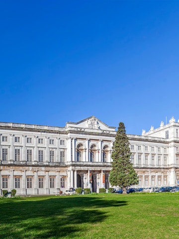 National Palace of Ajuda facade with green lawn in Lisbon, Portugal.
