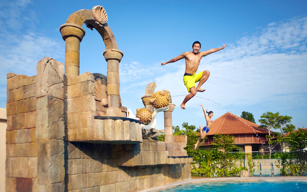 Visitors jumping into a pool at Adventure Cove Waterpark™, Singapore.