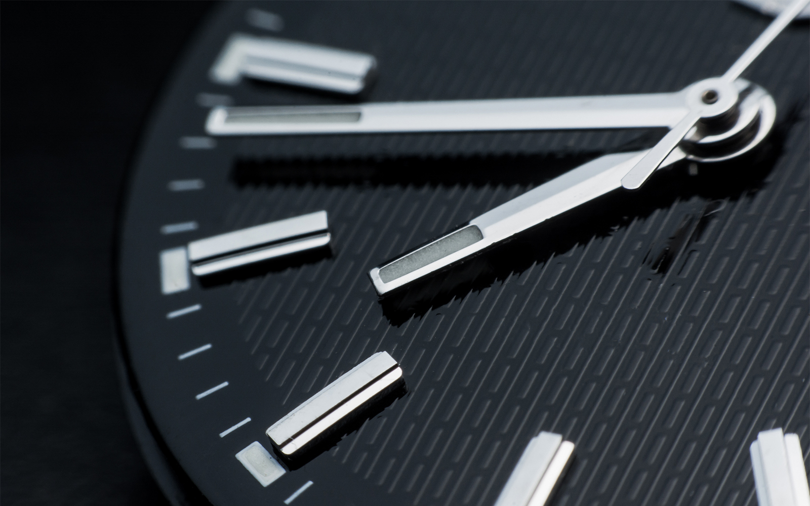 Close-up of a watch face showing time with silver hands and markers.