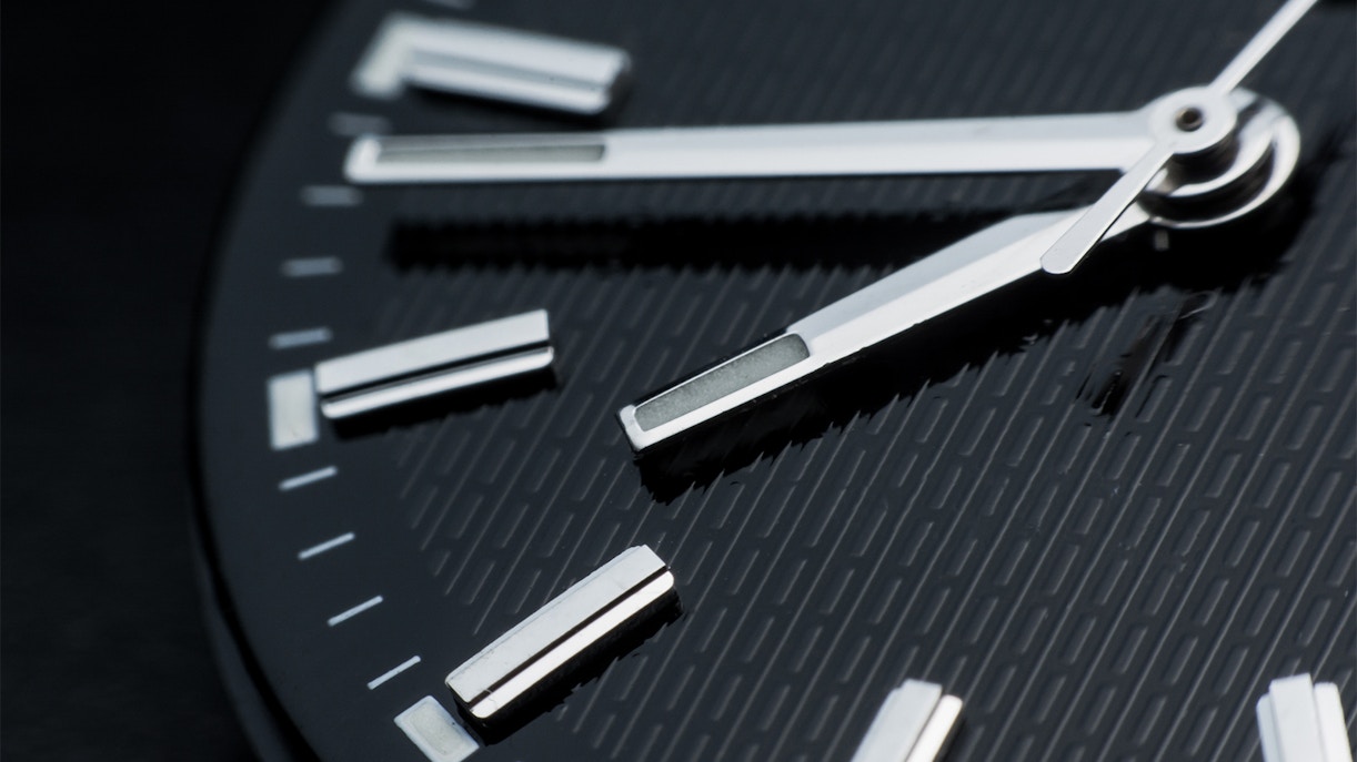 Close-up of a watch face showing time with silver hands and markers.