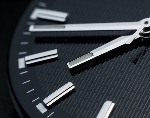 Close-up of a watch face showing time with silver hands and markers.