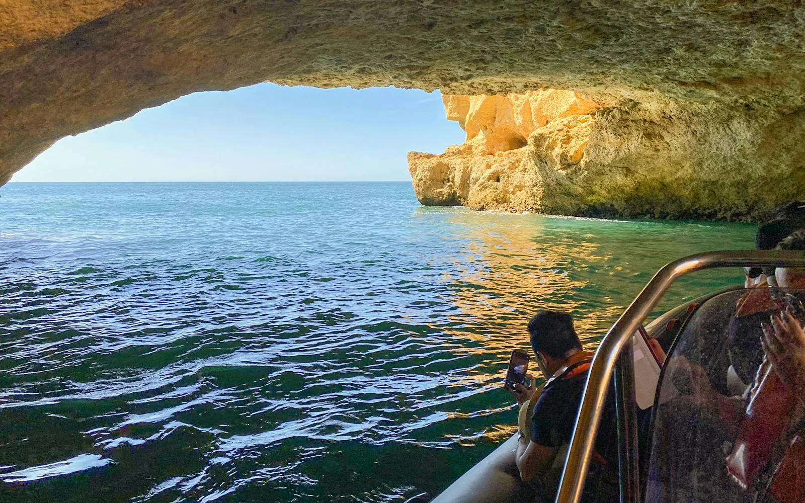 Tourist photographing Benagil Cave from a speedboat in Algarve, Portugal.