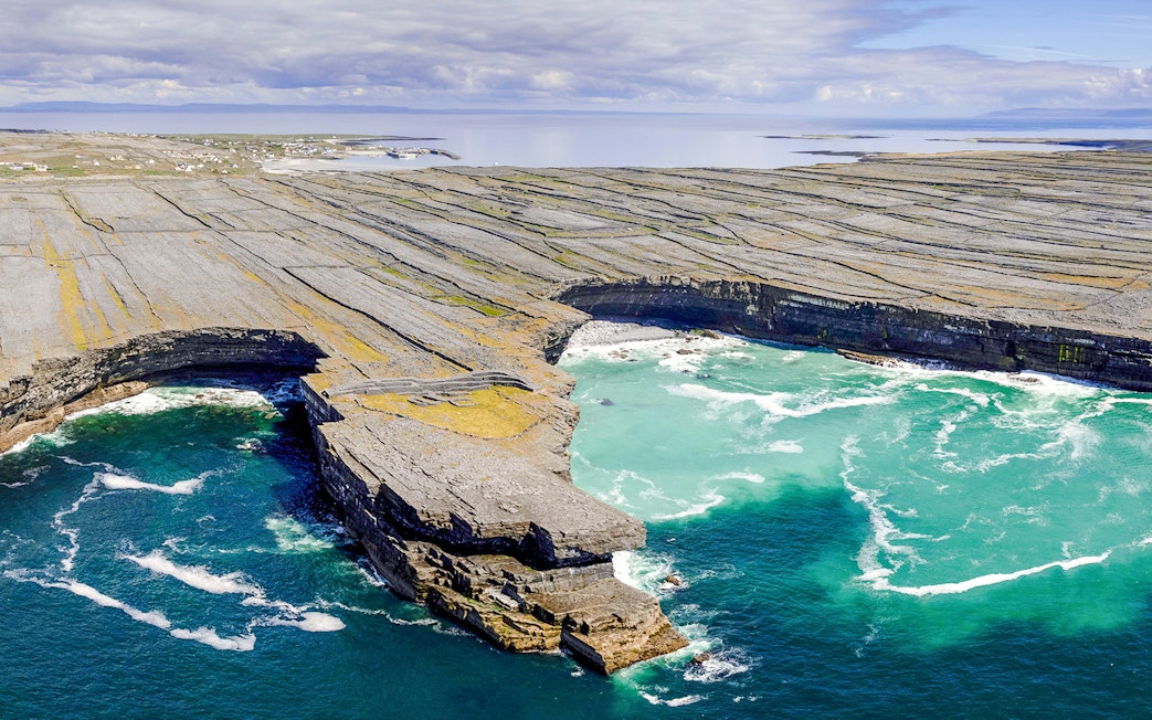 Rugged stone cliffs and turquoise waters of Aran Island, Ireland.