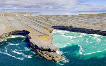 Rugged stone cliffs and turquoise waters of Aran Island, Ireland.