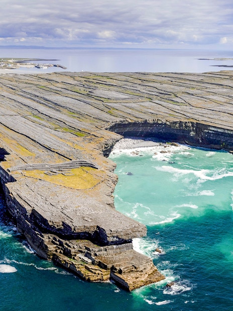 Rugged stone cliffs and turquoise waters of Aran Island, Ireland.