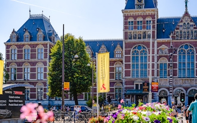 Rijksmuseum facade with canal tour signs in Amsterdam.