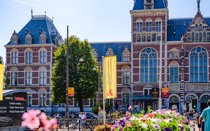 Rijksmuseum facade with canal tour signs in Amsterdam.