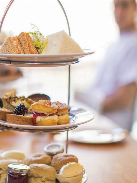Afternoon tea with scones, sandwiches, and pastries on a tiered stand at Westminster Abbey.