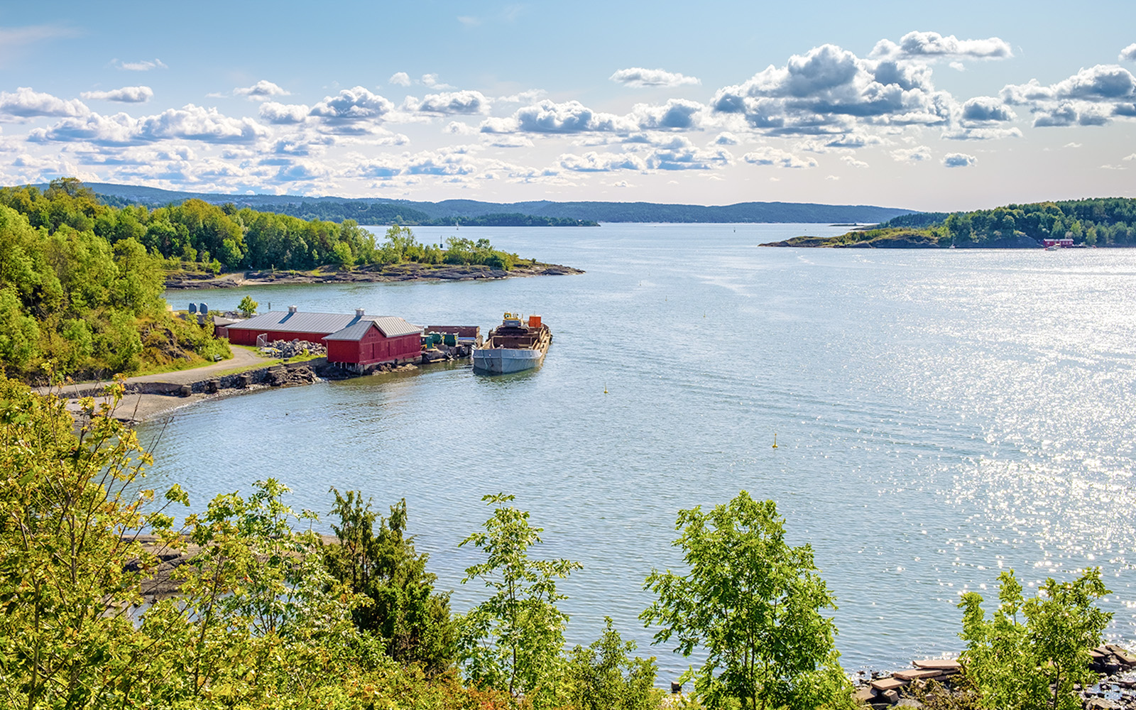 Panoramic view of Oslofjord harbor from Hovedoya island with red buildings and boat.