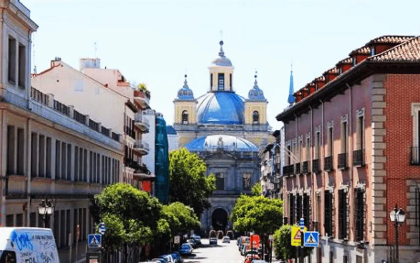 Street view of Madrid's Latin Quarter with a historic church in the background.