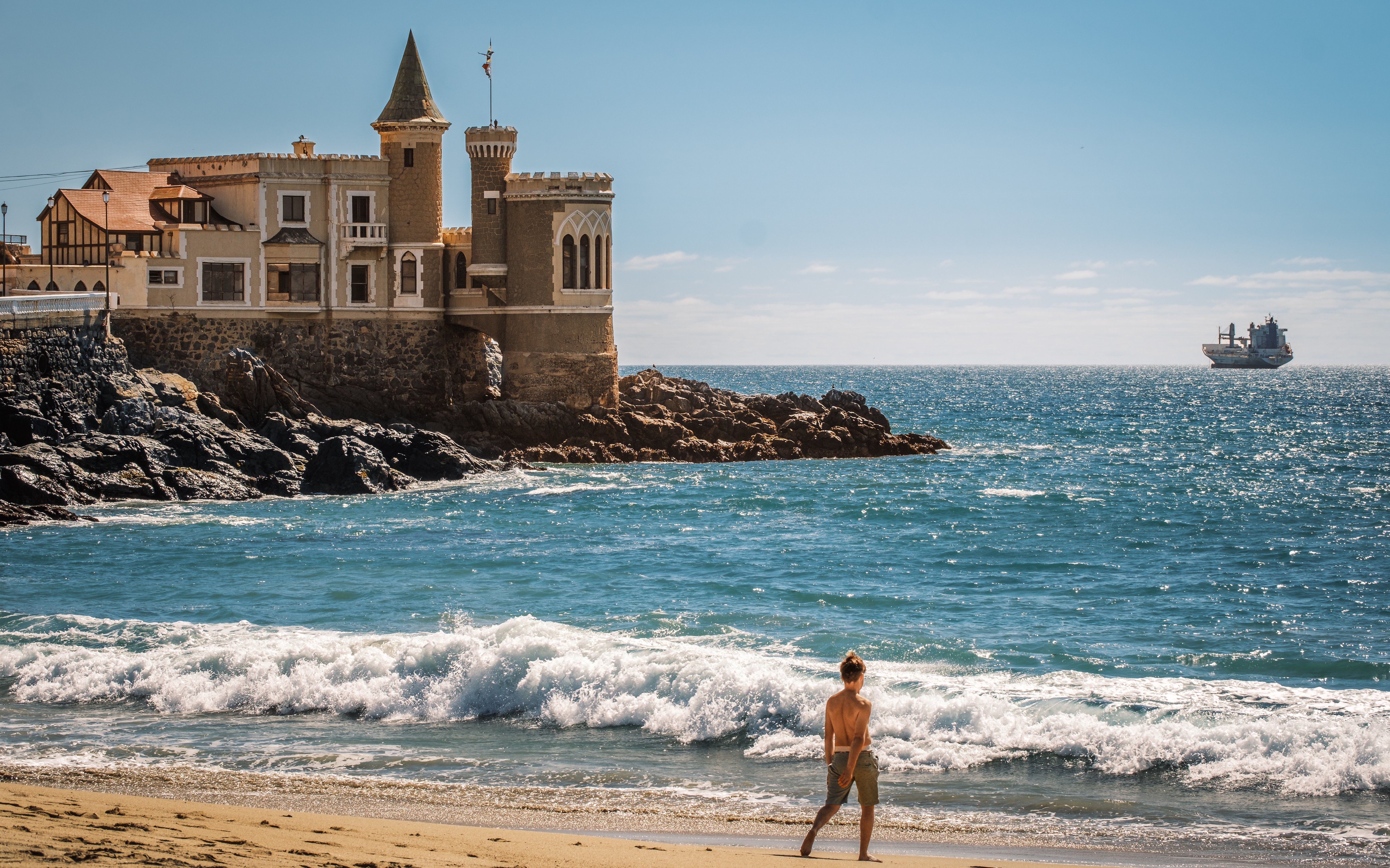 Wulff Castle on the rocky coast of Vina del Mar, Chile, with a ship in the distance.