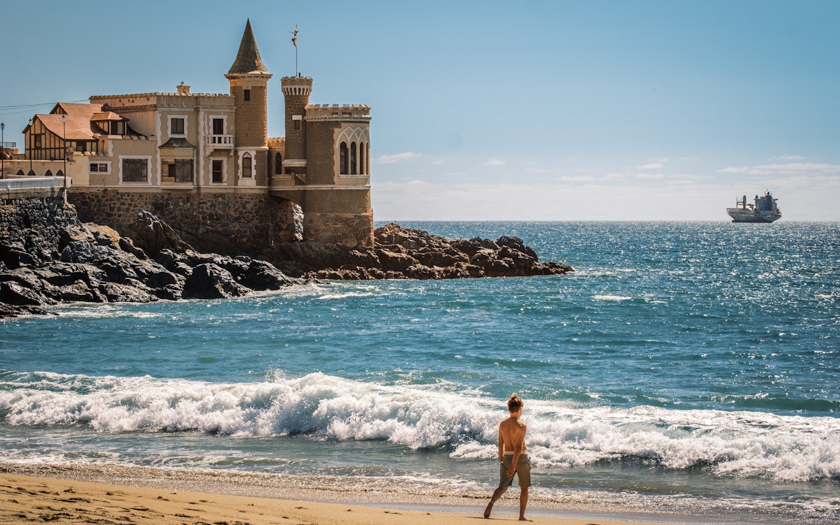 Wulff Castle on the rocky coast of Vina del Mar, Chile, with a ship in the distance.