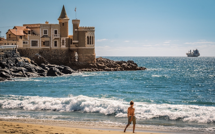 Wulff Castle on the rocky coast of Vina del Mar, Chile, with a ship in the distance.