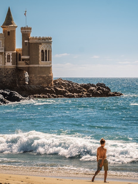 Wulff Castle on the rocky coast of Vina del Mar, Chile, with a ship in the distance.