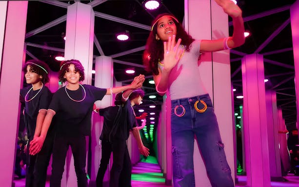 Kids exploring Mirror Maze at American Dream, surrounded by colorful reflections.