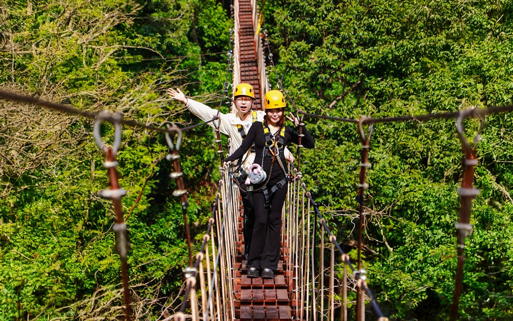 Two people crossing a suspension bridge during Flying Hanuman zipline adventure in Phuket.