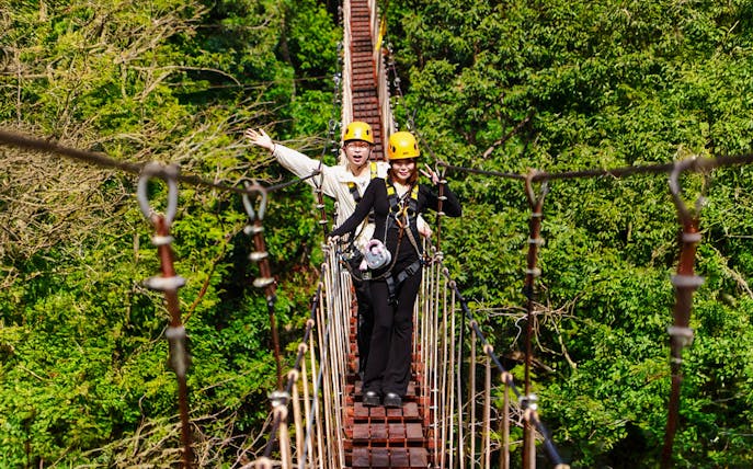 Two people crossing a suspension bridge during Flying Hanuman zipline adventure in Phuket.